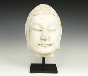 This marble Buddha head is distinctly Chinese with a round face and almost absent top knot