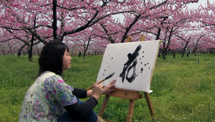 Seiran writing calligraphy outdoors among the cherry blossoms