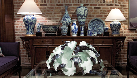 Collection of antique Chinese porcelain flanked by contemporary table lamps behind porcelain sculpture